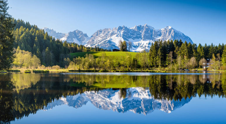 Idyllic alpine scenery, snowy mountains mirroring in a small lake, Kitzbuehel, Tyrol, Austria